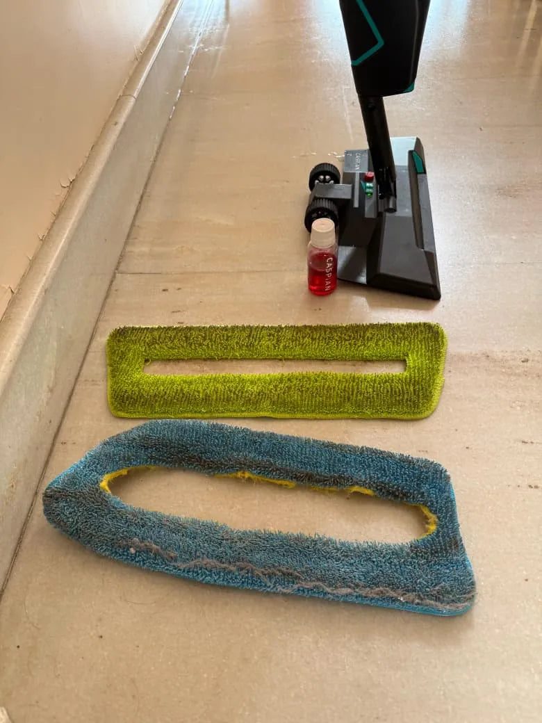 Two used SmartMop pads, green and blue, beside the SmartMop and a Caspian floor cleaner bottle