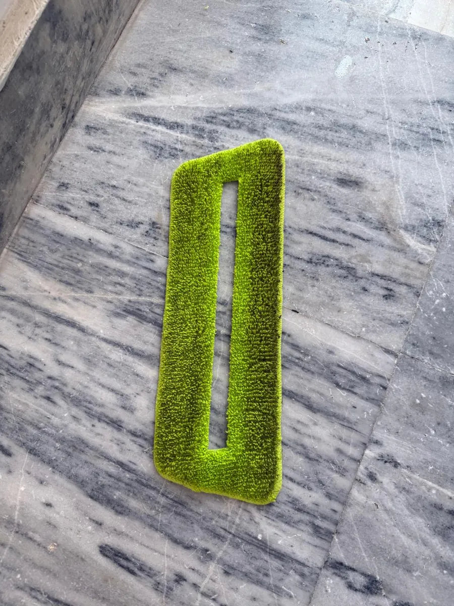 A green SmartMop microfiber pad on a marble floor, grey with dirt after one session