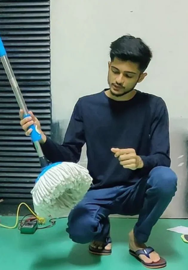 Mehul Chouhan, co-founder of Caspian, crouching with an ordinary spin mop in the workshop